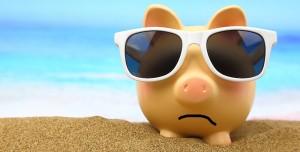 Summer piggy bank with sunglasses on the beach